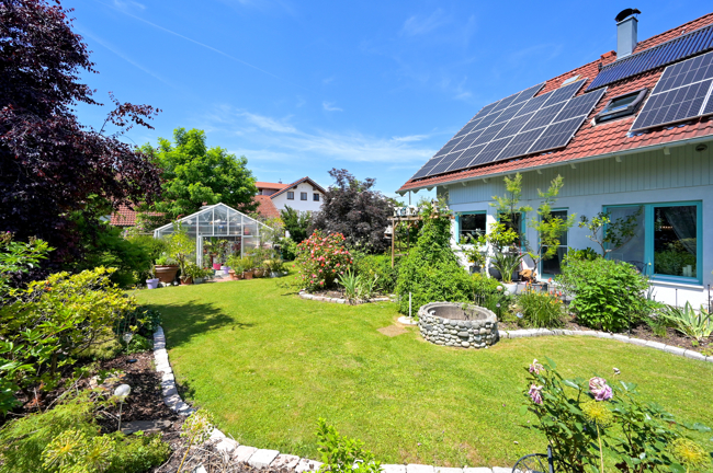 sonniger Garten mit Gewächshaus